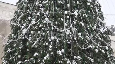 大圣诞树，有银色的玩具和灯光，在大雪纷飞的大雪中落下